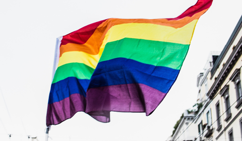 Pride flag flying with a building in the background