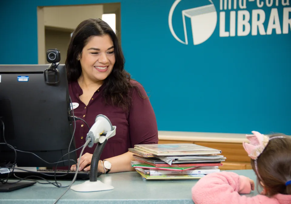 MCL staff member answers questions from a young customer at the service desk. 