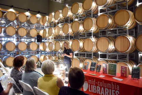 Presenter with wine barrels in the background and participants listening from front row.