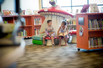 Two children sit on large mushrooms at the West Pasco library